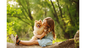 girl sitting on log with pomeranian dog on her lap